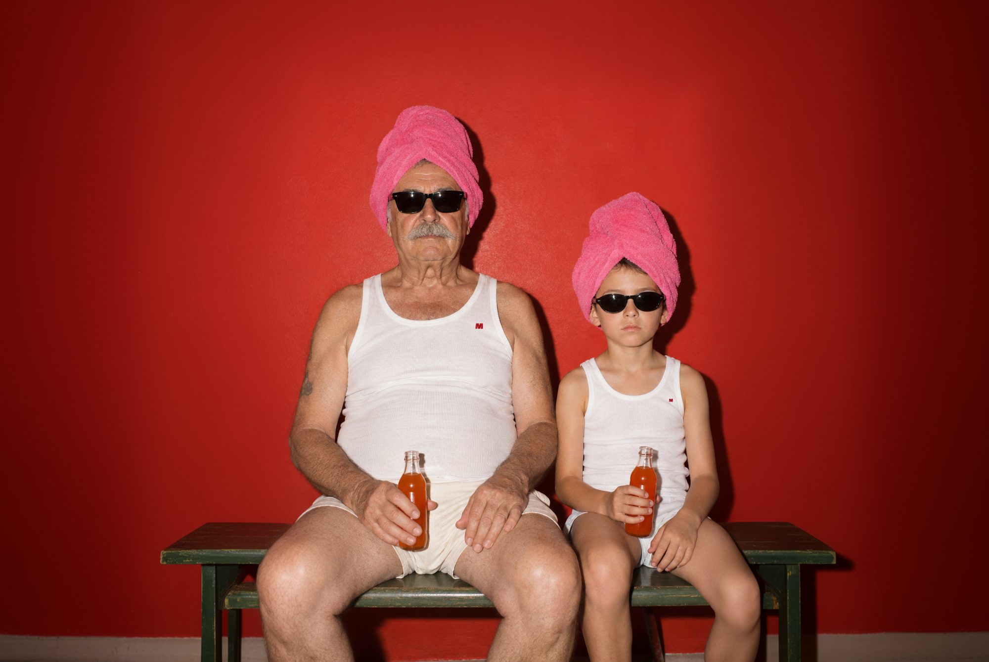 A grandfather and grandson in white Marcellekes, pink towels on their heads