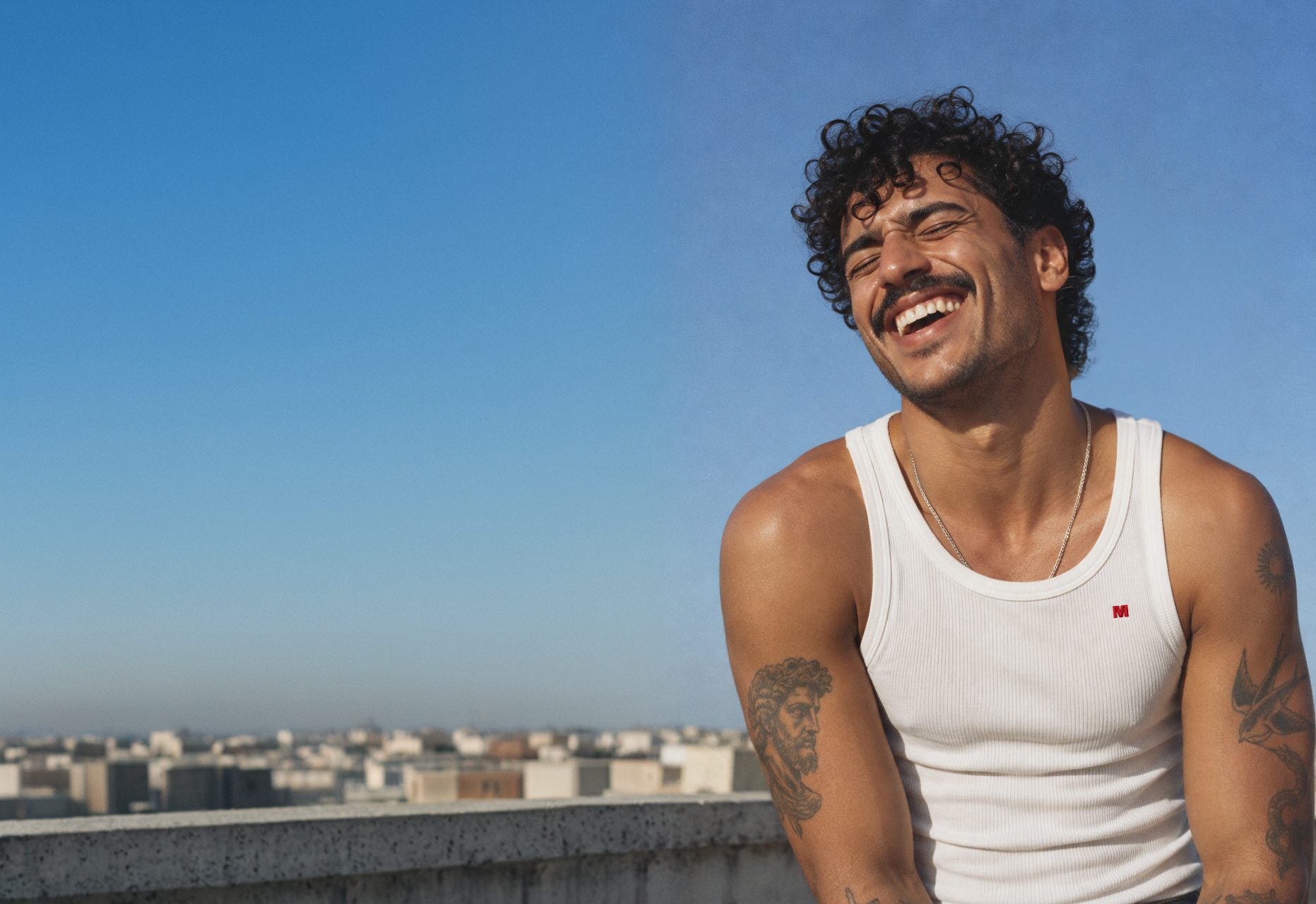 A man in a Marcelleke laughing on a rooftop